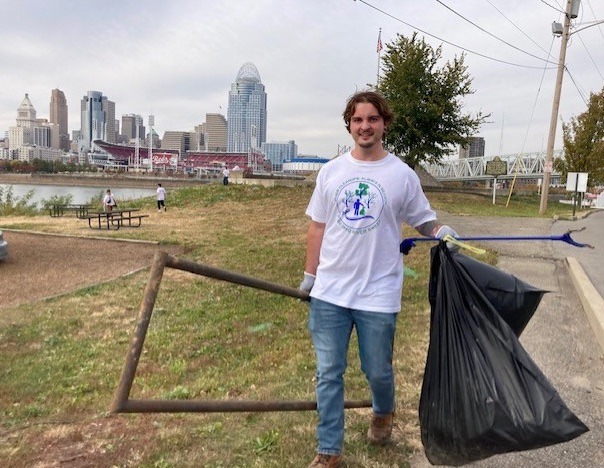 Student carrying garbage bag and large piece of metal debris