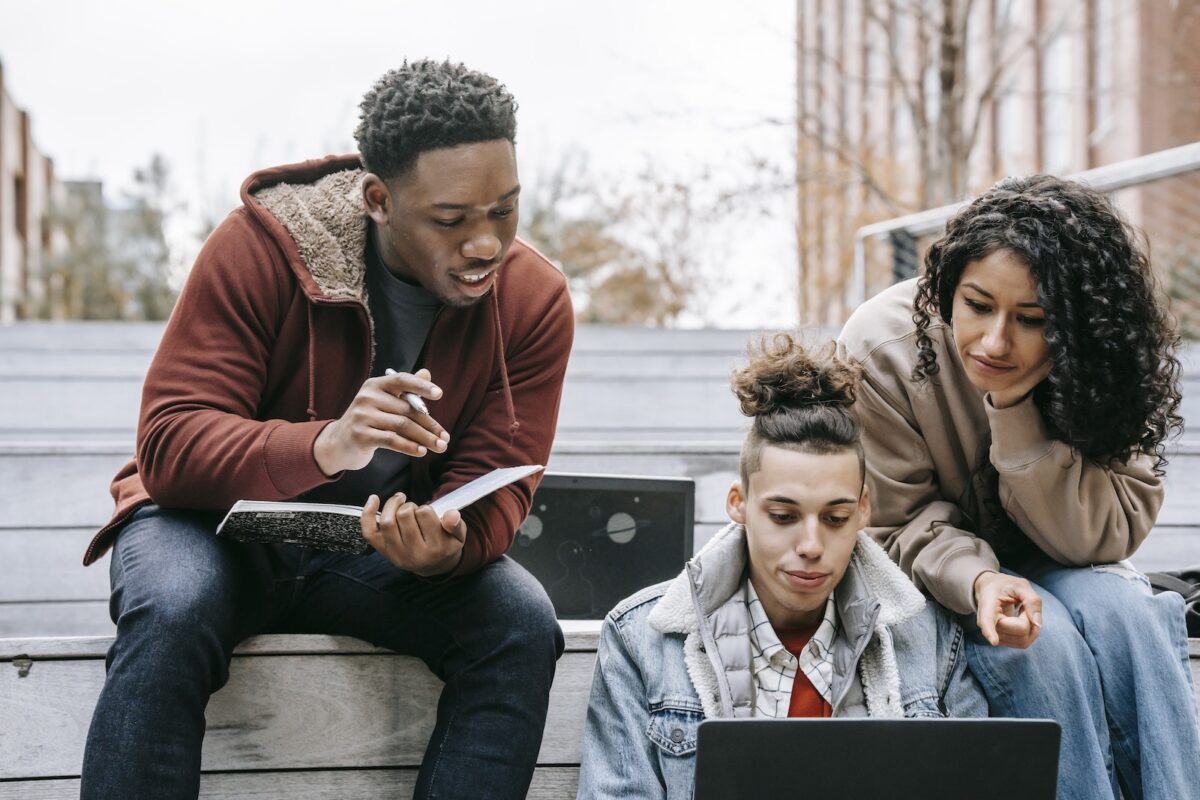 three students looking at a laptop computer