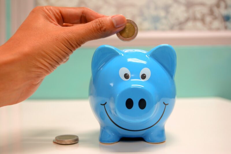 hand putting coin into blue piggy bank