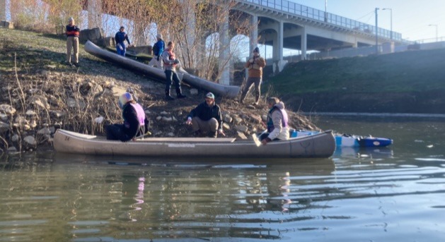 Students carry canoes down the riverbank