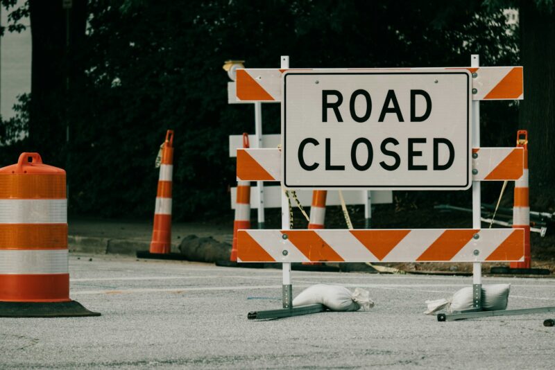 a road closed sign near orange cones