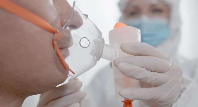 Close up photo of respiratory technician placing a breathing apparatus on a patient