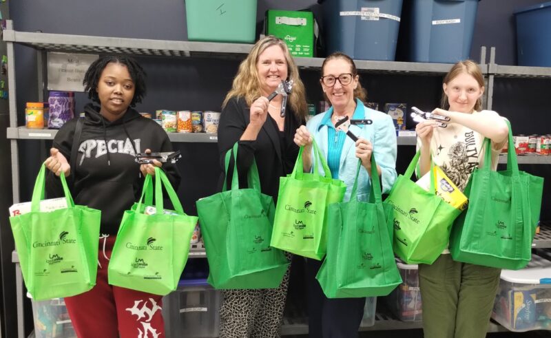 Showing off the new tote bags and can openers for Food Pantry customers are Environmental Club member La’Star Pugh, Professor Ann Fallon, Food Pantry Facilitator Angela Haensel, and Environmental Club member Melissa Goetz